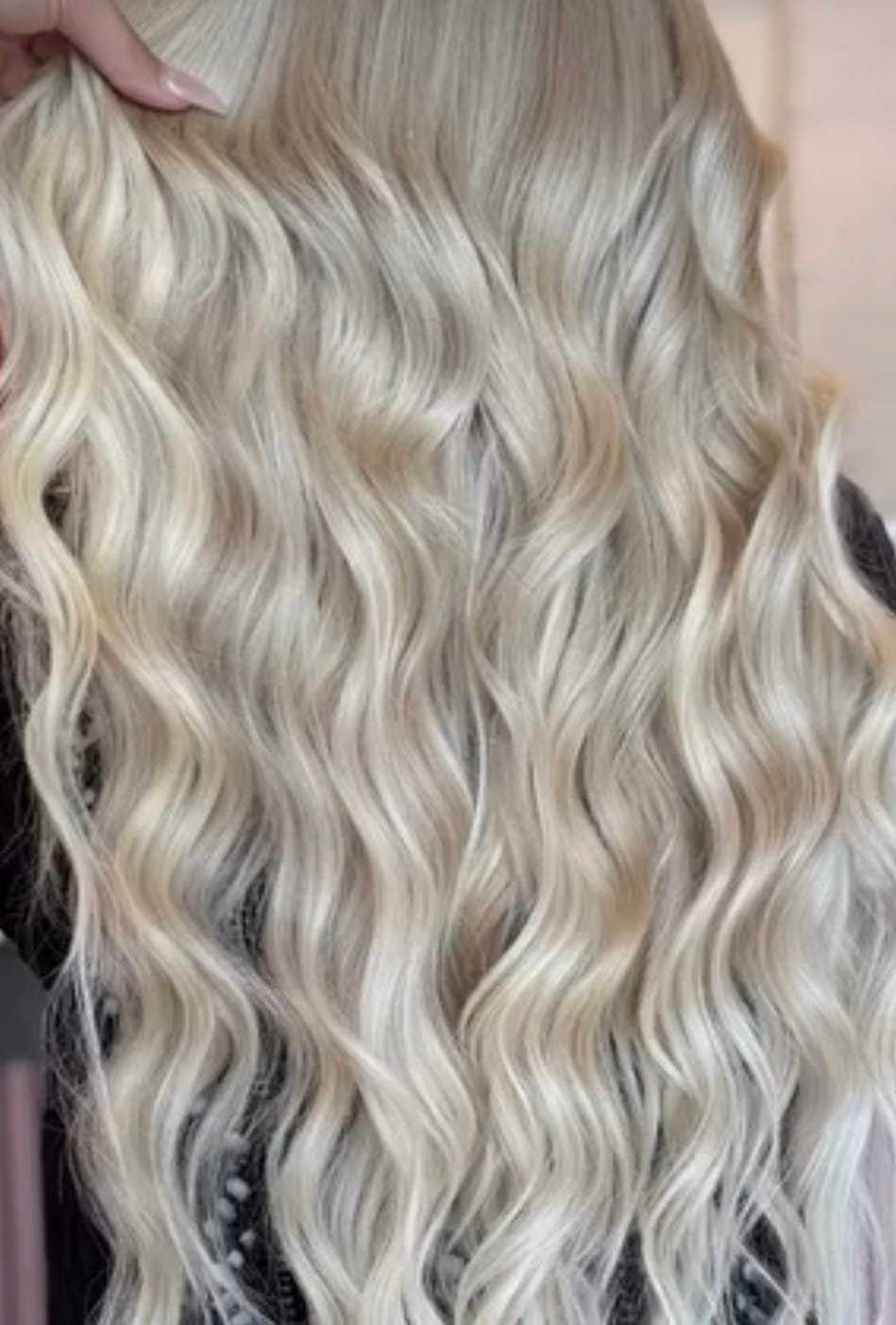 Wavy platinum blonde hair with soft curls cascading down the back.